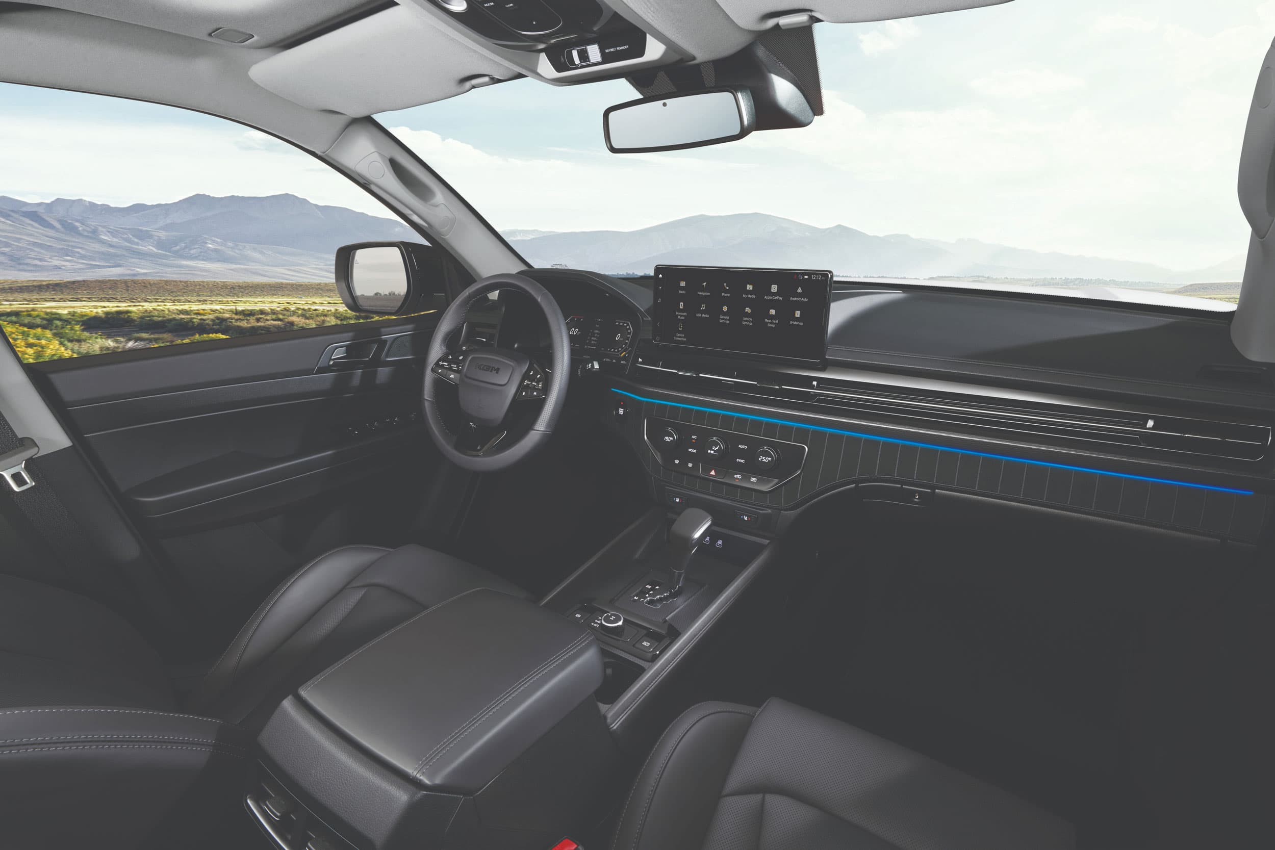 Modern car interior with a digital dashboard, multifunction steering wheel, and sleek design. Desert landscape visible through the window.