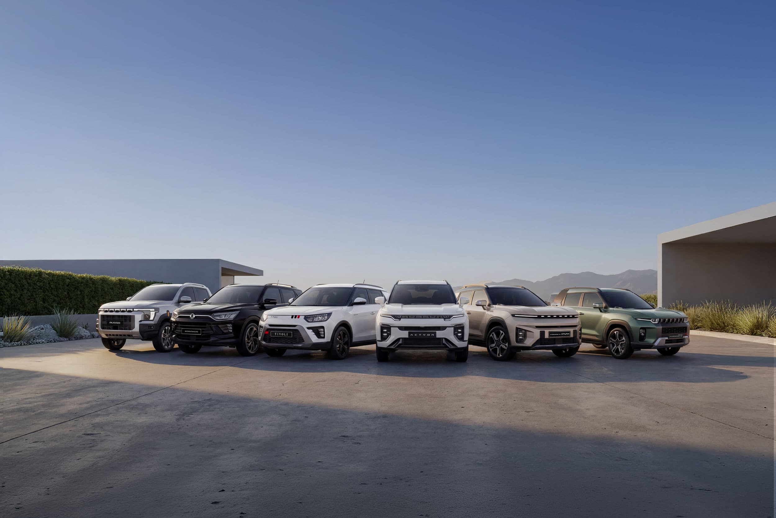 A lineup of six modern KGMs parked on a concrete surface with a clear blue sky and minimalist architecture in the background.