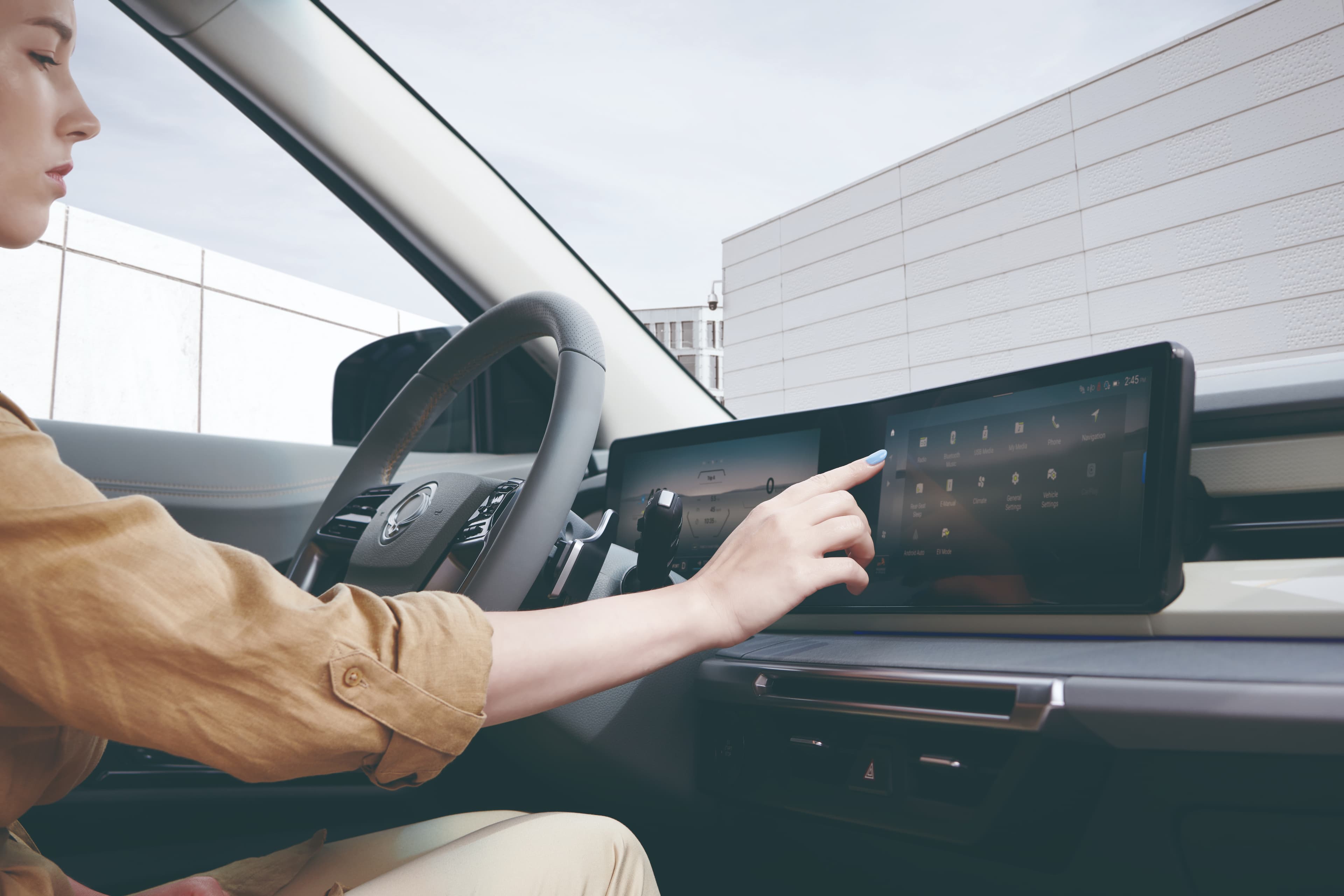 Een close-up van het interieur van de Torres EVX met een vrouw die het digitaal instrumentenpaneel gebruikt en iets aanduidt op het doorlopende scherm