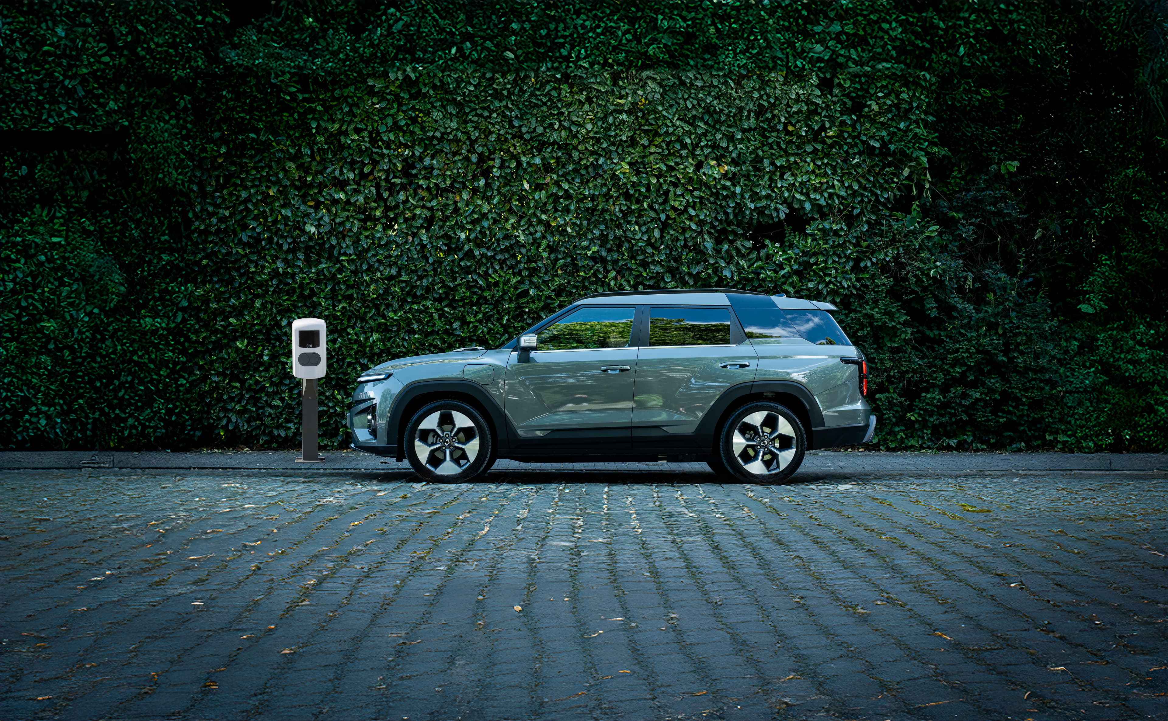 De Torres EVX in Forest Green kleur die horizontaal geparkeerd staat aan een laadpaal