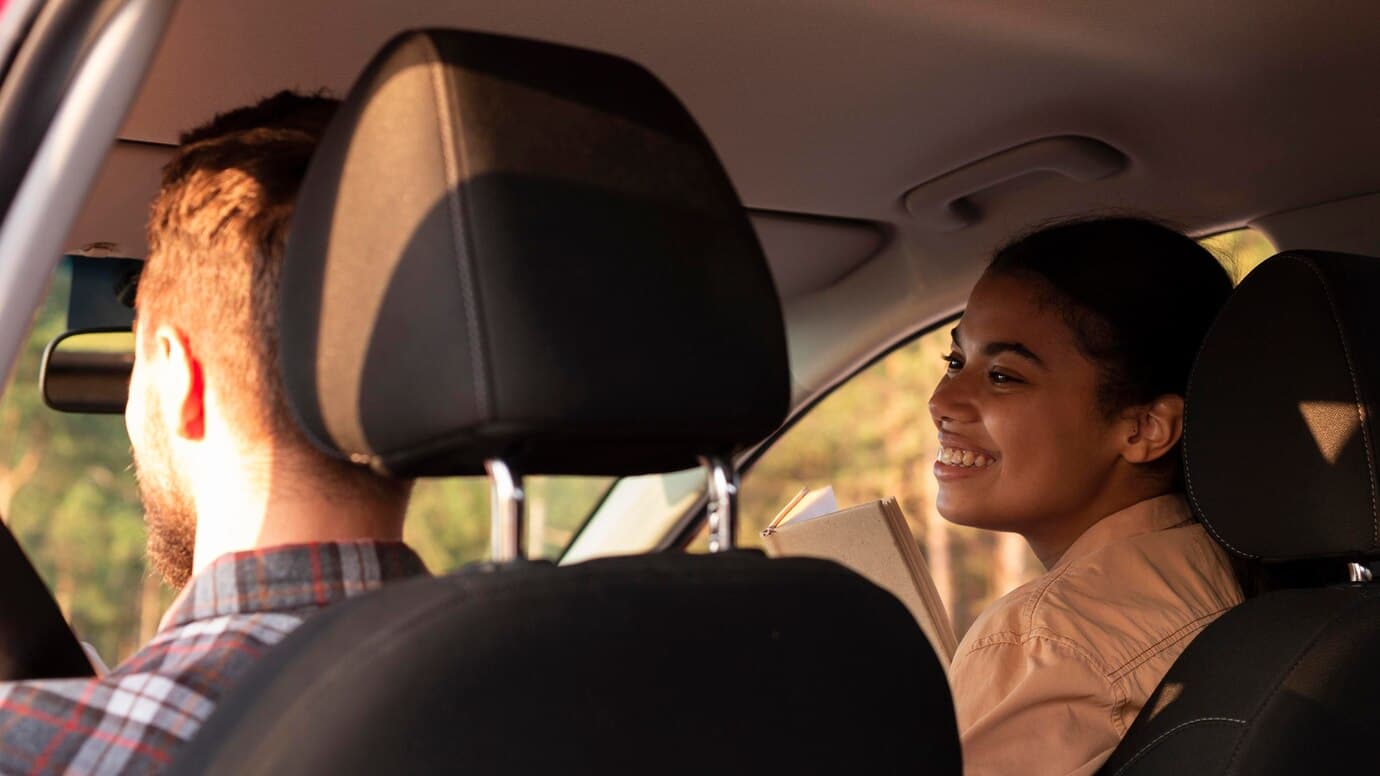 Een man en vrouw in de auto met de hoofdsteunen van de bestuurders en passagiersstoel in het zicht.